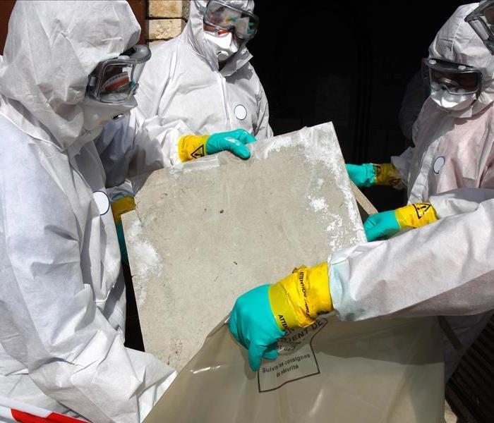 people wearing required hazmat suits and ppe disposing of asbestos material